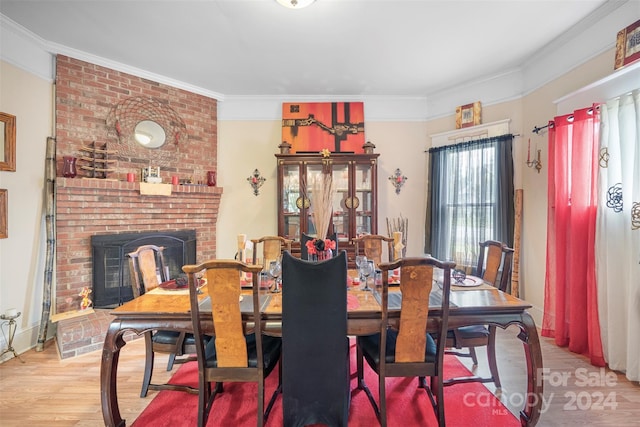 dining room with a brick fireplace, crown molding, and wood-type flooring