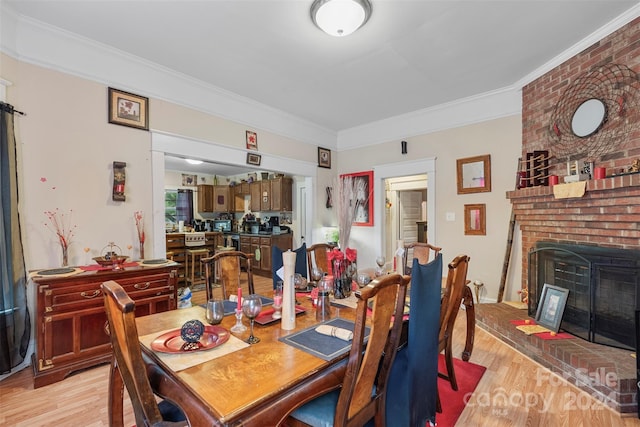 dining room featuring crown molding, a fireplace, and light hardwood / wood-style flooring