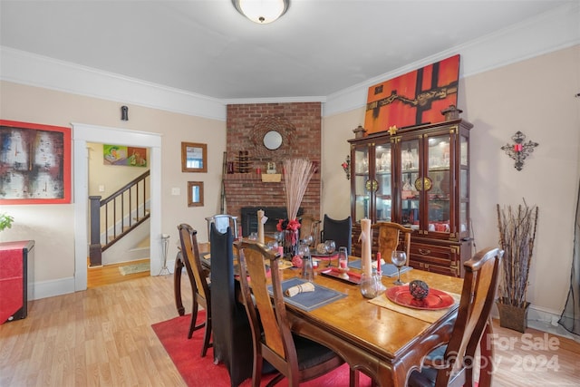 dining area with light hardwood / wood-style floors, ornamental molding, and a fireplace