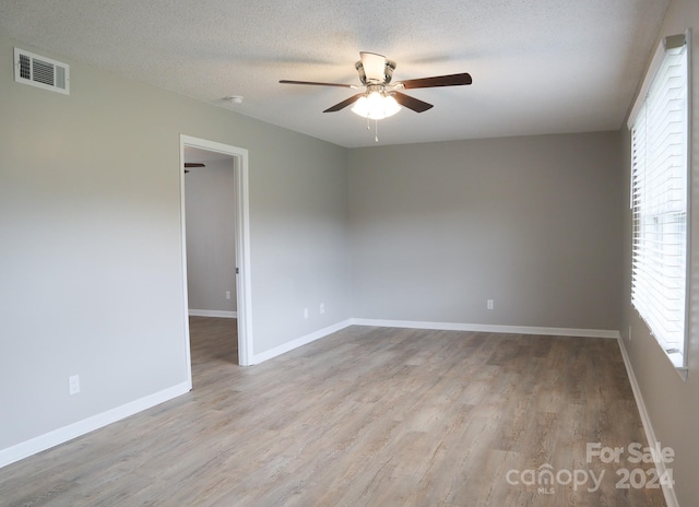 unfurnished room featuring light hardwood / wood-style floors, ceiling fan, and a textured ceiling