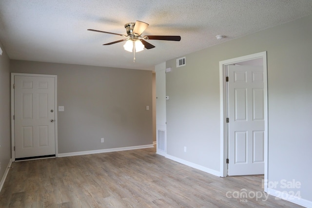 spare room featuring light hardwood / wood-style floors, ceiling fan, and a textured ceiling