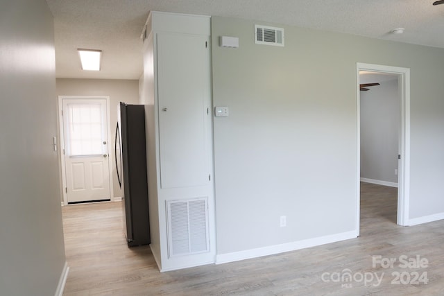 corridor featuring a textured ceiling and light hardwood / wood-style flooring