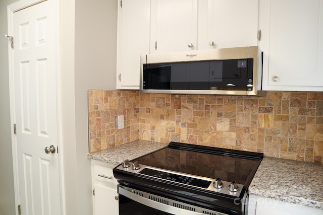 kitchen featuring appliances with stainless steel finishes, decorative backsplash, white cabinetry, and light stone countertops