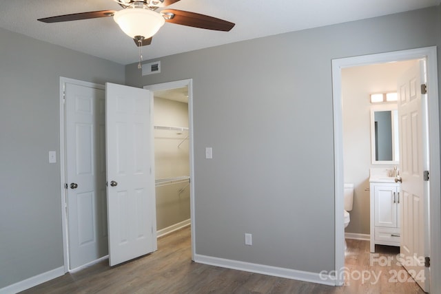 unfurnished bedroom featuring a textured ceiling, dark wood-type flooring, sink, ensuite bath, and ceiling fan