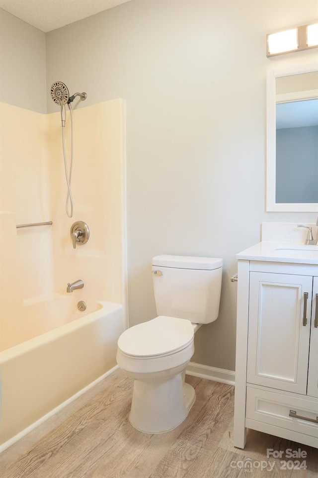 full bathroom with a textured ceiling, hardwood / wood-style flooring, bathing tub / shower combination, vanity, and toilet