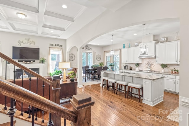 interior space featuring light wood-type flooring, beamed ceiling, sink, crown molding, and coffered ceiling