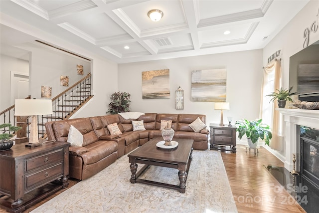 living room featuring beamed ceiling, a premium fireplace, coffered ceiling, hardwood / wood-style flooring, and crown molding