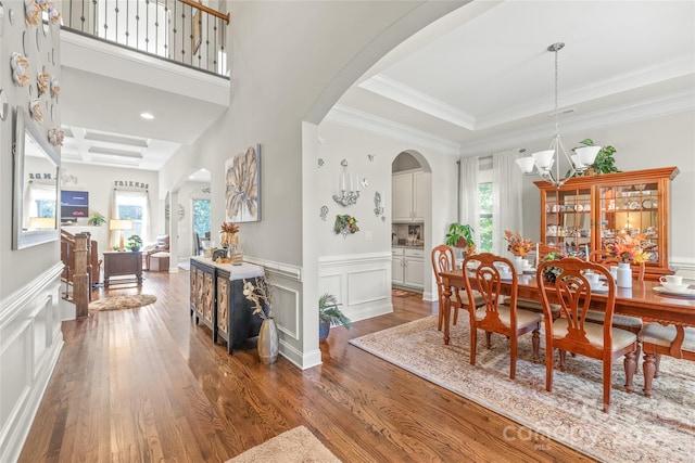 dining space with ornamental molding, a raised ceiling, dark hardwood / wood-style flooring, and a healthy amount of sunlight