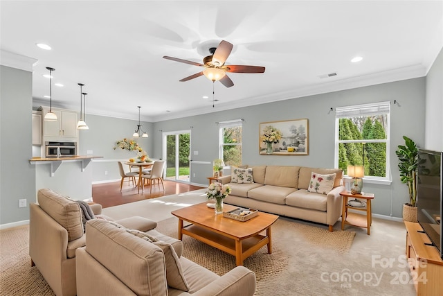 carpeted living room with crown molding, plenty of natural light, and ceiling fan