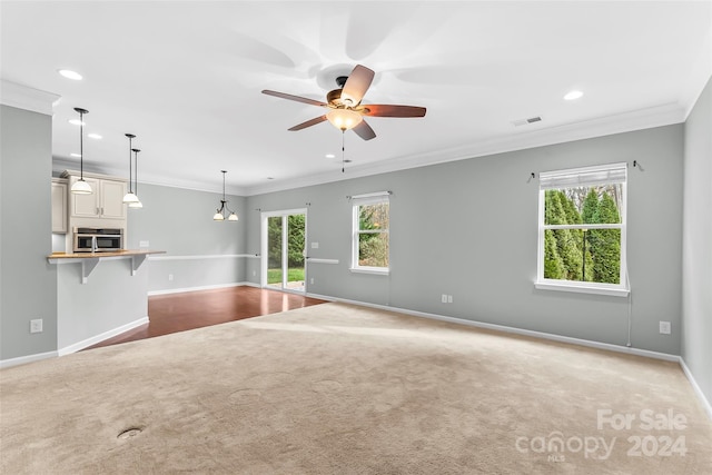 unfurnished living room with crown molding, plenty of natural light, and ceiling fan with notable chandelier