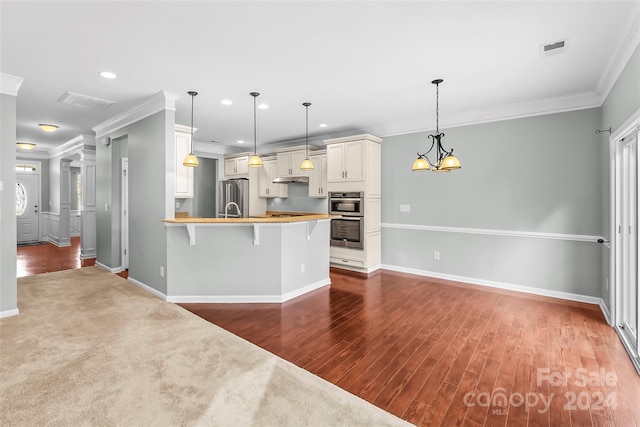 kitchen with pendant lighting, crown molding, a breakfast bar area, and hardwood / wood-style floors