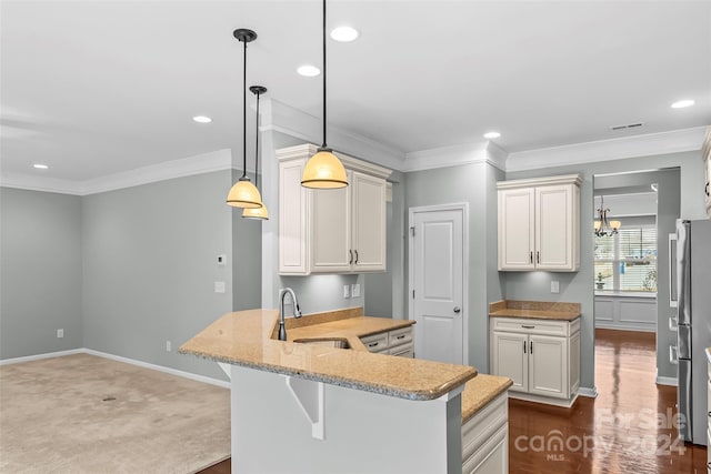 kitchen with light stone countertops, stainless steel fridge, ornamental molding, sink, and decorative light fixtures