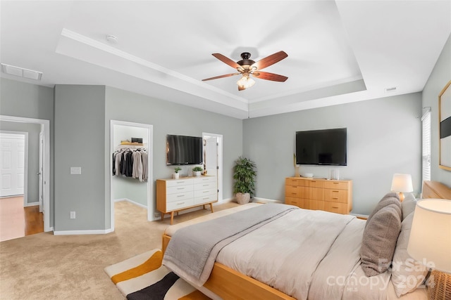 carpeted bedroom featuring a raised ceiling, a spacious closet, a closet, and ceiling fan