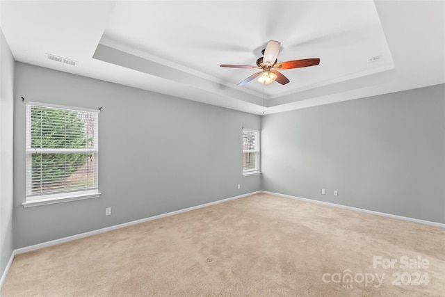 carpeted spare room featuring a tray ceiling, ceiling fan, and crown molding