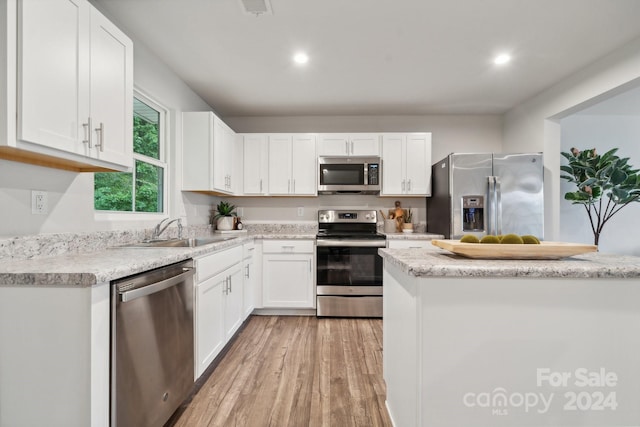 kitchen with white cabinets, stainless steel appliances, sink, and light hardwood / wood-style flooring