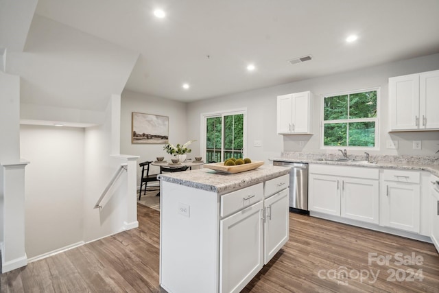 kitchen featuring light wood-type flooring, stainless steel dishwasher, a kitchen island, and white cabinets