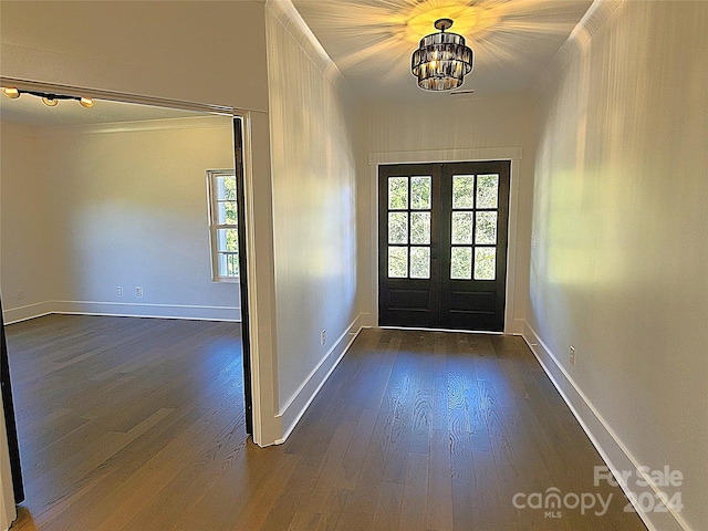 entryway with dark wood-type flooring, a notable chandelier, and french doors