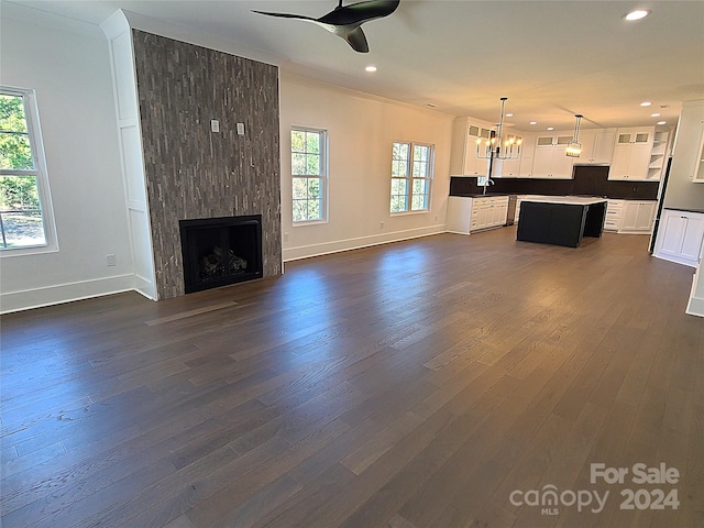 unfurnished living room with a wealth of natural light, dark wood-type flooring, and a large fireplace