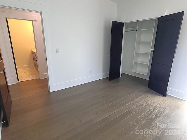 unfurnished bedroom featuring a closet and dark hardwood / wood-style flooring