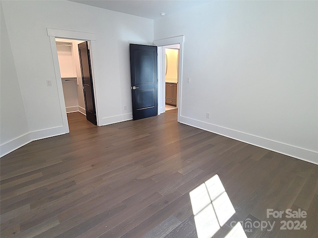 unfurnished bedroom featuring a closet, a spacious closet, and dark hardwood / wood-style flooring