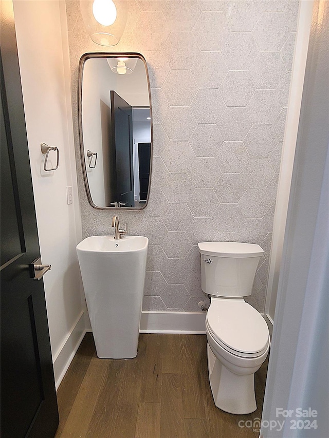 bathroom with toilet, tile walls, sink, and hardwood / wood-style floors