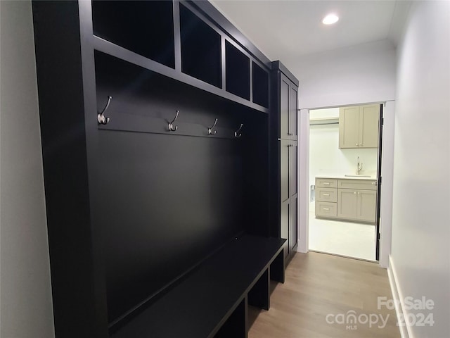 mudroom with sink and light hardwood / wood-style flooring