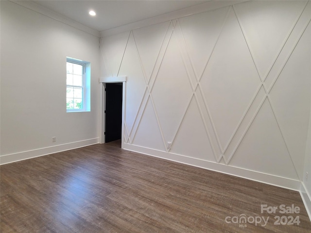 unfurnished room featuring dark wood-type flooring and crown molding