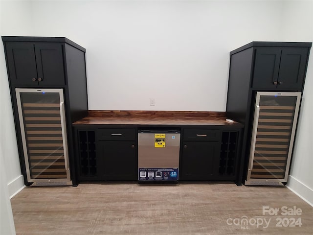 bar with light hardwood / wood-style flooring, beverage cooler, and stainless steel refrigerator