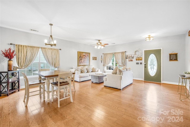 living room featuring ceiling fan with notable chandelier, light hardwood / wood-style flooring, and a healthy amount of sunlight