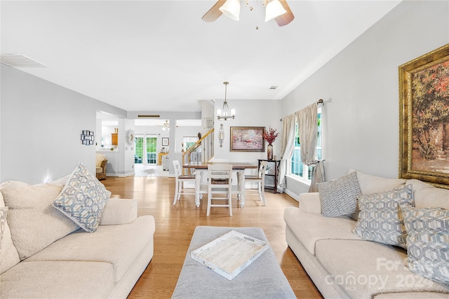 living room featuring light wood-type flooring and ceiling fan with notable chandelier