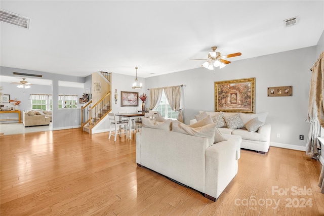 living room featuring light wood-type flooring and ceiling fan with notable chandelier