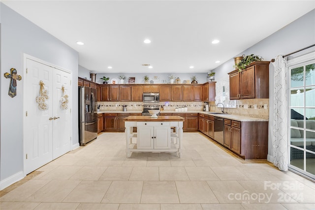 kitchen with tasteful backsplash, light tile patterned floors, stainless steel appliances, a center island, and sink