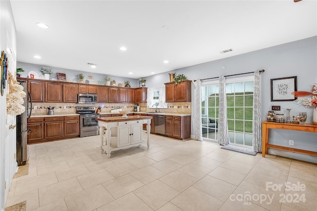 kitchen with sink, a kitchen island, a kitchen breakfast bar, stainless steel appliances, and decorative backsplash