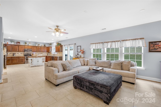 tiled living room with ceiling fan and sink