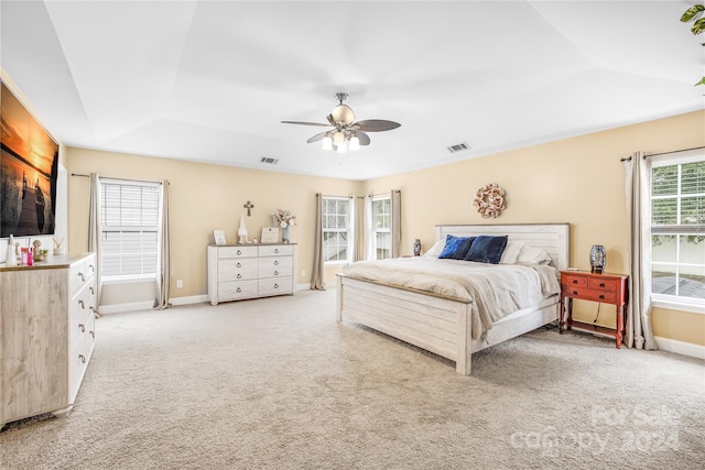 carpeted bedroom with ceiling fan and a tray ceiling