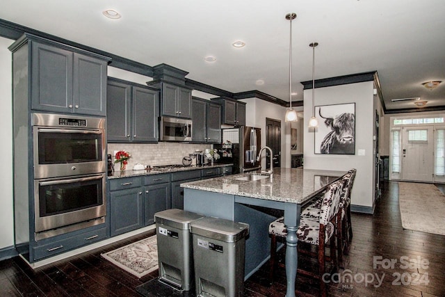 kitchen with hanging light fixtures, light stone counters, stainless steel appliances, ornamental molding, and dark hardwood / wood-style floors