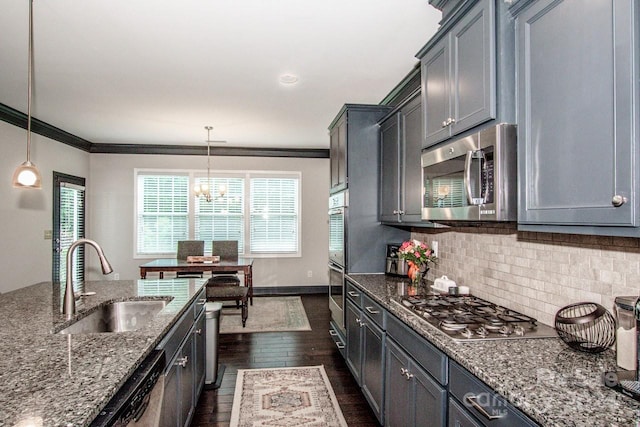 kitchen featuring appliances with stainless steel finishes, dark stone countertops, sink, and decorative light fixtures