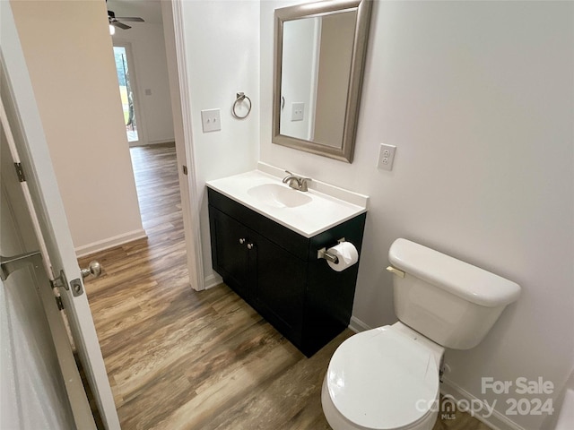 bathroom with wood-type flooring, vanity, toilet, and ceiling fan