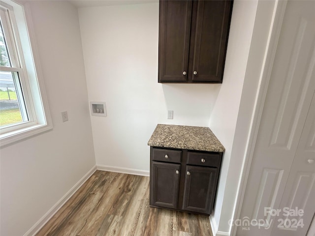 washroom with cabinets, hookup for a washing machine, and light hardwood / wood-style floors