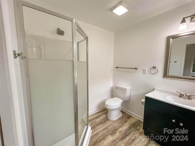 bathroom with wood-type flooring, vanity, toilet, and an enclosed shower