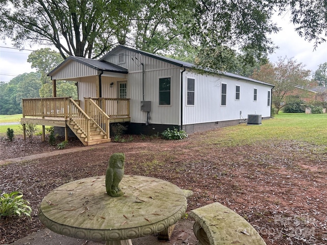 view of front of house featuring a wooden deck, central AC unit, and a front yard