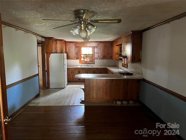 kitchen with gas stovetop, kitchen peninsula, white fridge, light hardwood / wood-style flooring, and ceiling fan