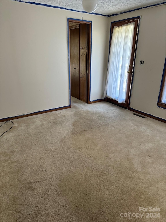 carpeted empty room with a textured ceiling