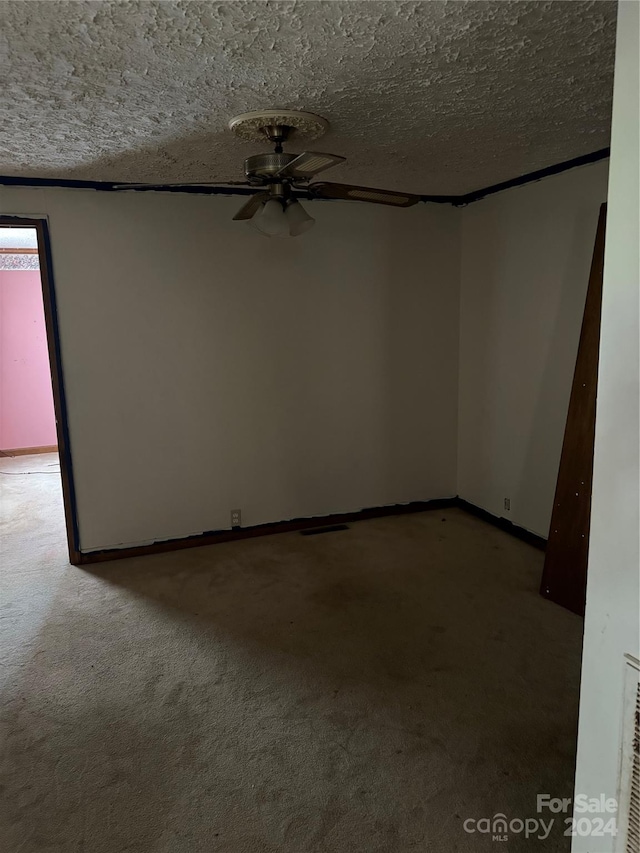 empty room with a textured ceiling, carpet, and ceiling fan