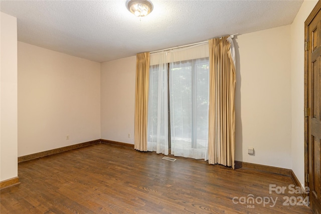 unfurnished room with a textured ceiling and dark hardwood / wood-style floors