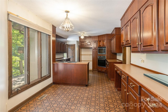 kitchen with decorative light fixtures, oven, ceiling fan with notable chandelier, and stainless steel microwave