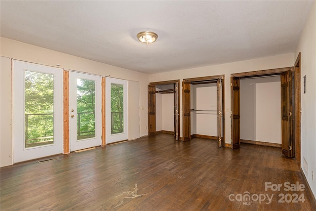 unfurnished bedroom with access to outside, a textured ceiling, and dark hardwood / wood-style floors