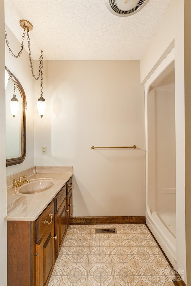 bathroom with vanity, a shower, a textured ceiling, and tile patterned floors