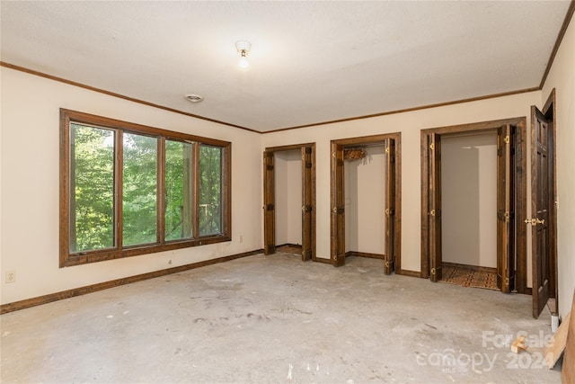 unfurnished bedroom featuring two closets, a textured ceiling, and ornamental molding