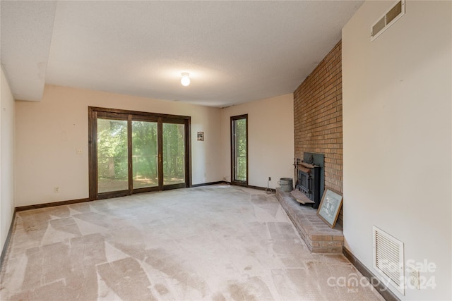 unfurnished living room featuring a wood stove, light carpet, and a textured ceiling